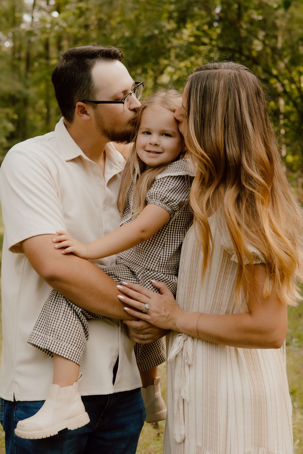 Family sharing tender moments and embraces during a casual outdoor photoshoot in nature.
