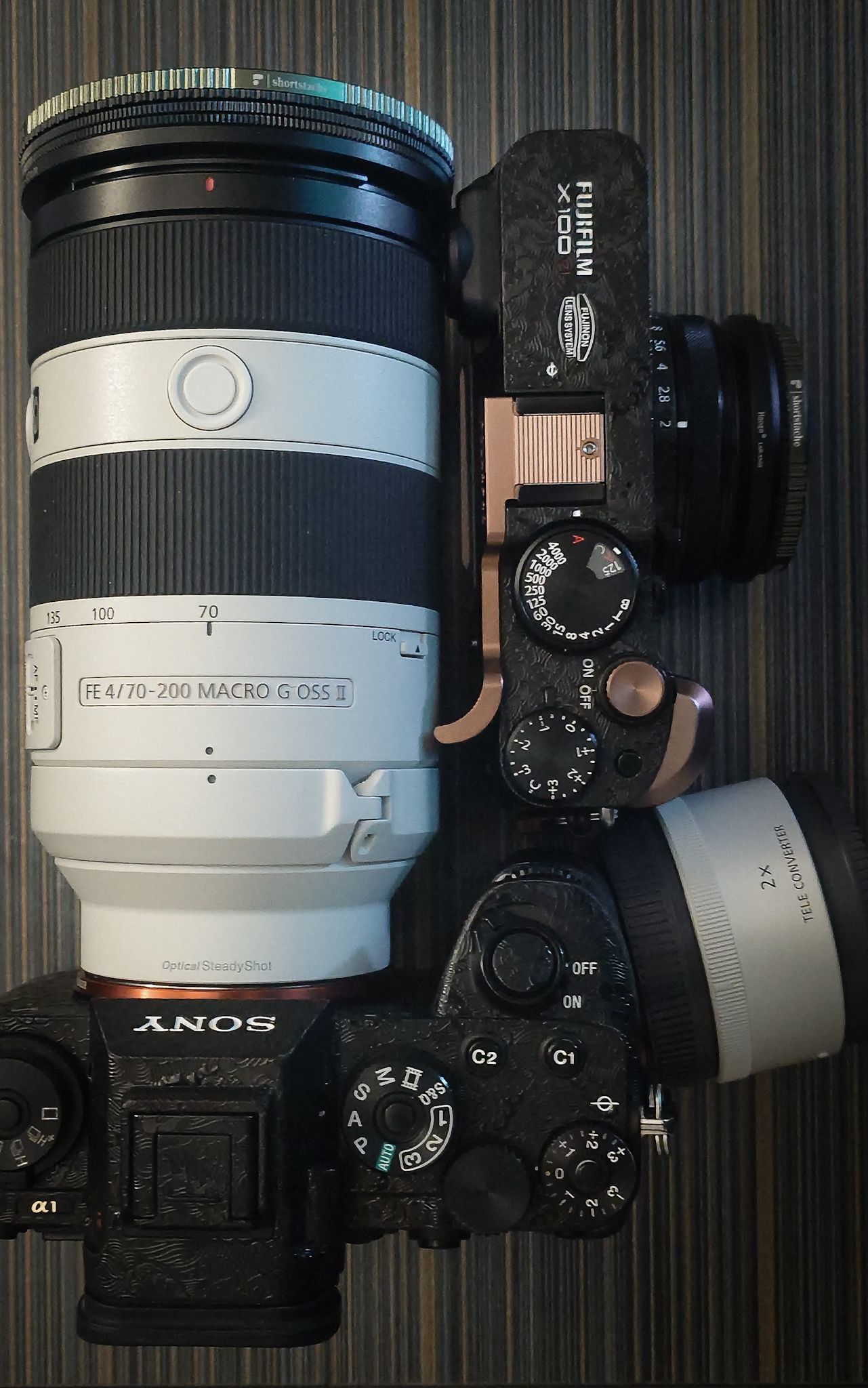 Top view of white telephoto lens mounted on Sony camera body showing dials and controls against dark background.