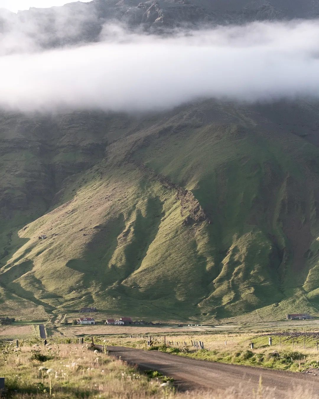 Moody green mountain landscape with low clouds drifting across the peaks.