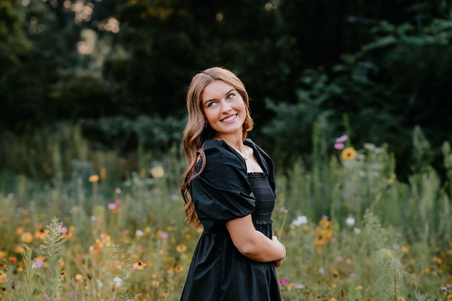 Dreamy outdoor portrait among yellow wildflowers and tall grass in natural lighting.