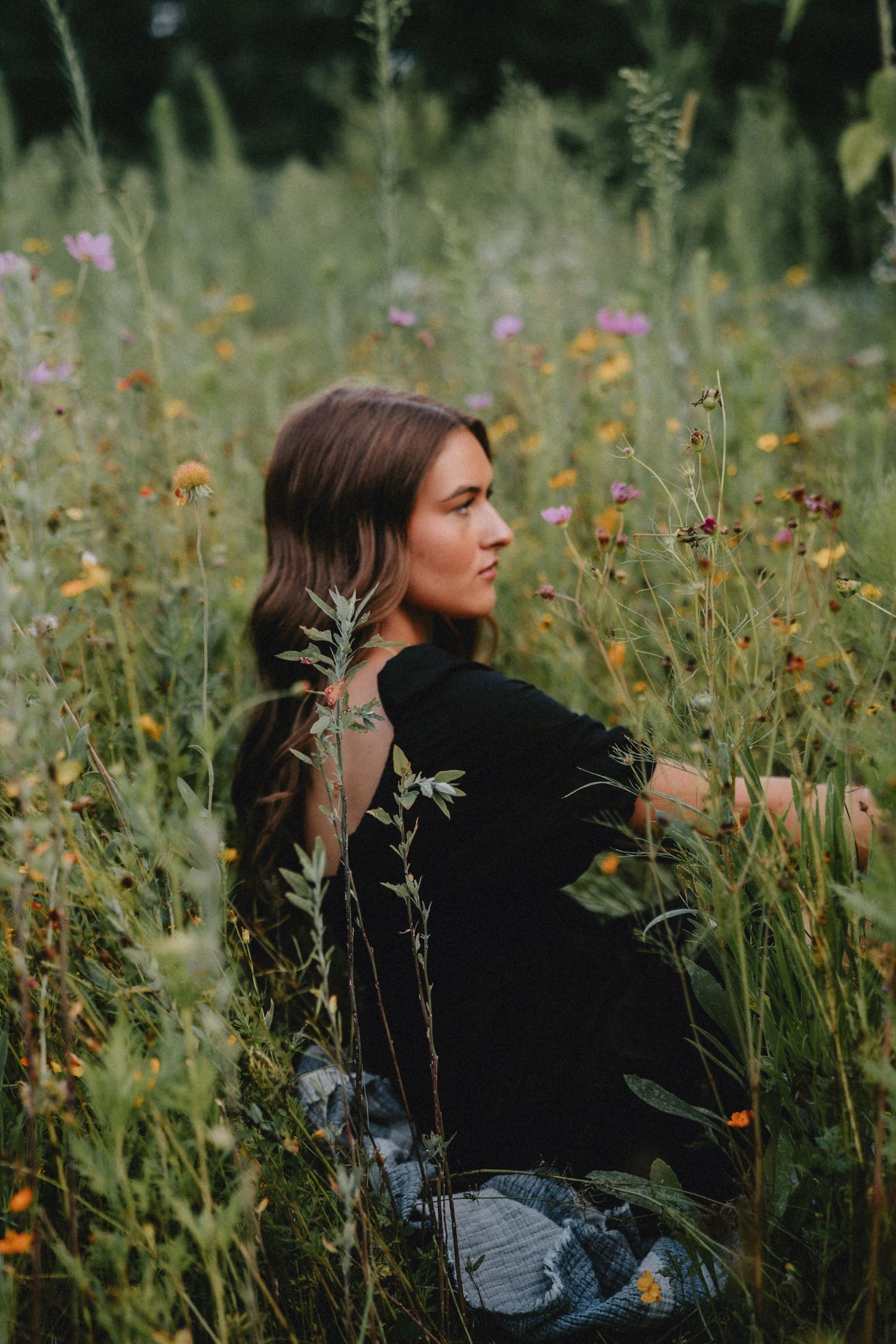 Side profile portrait in a meadow with yellow wildflowers and natural golden hour lighting.