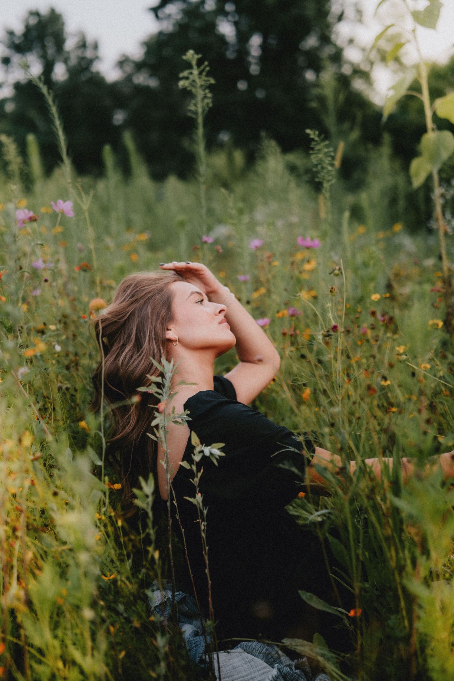 Expressive outdoor portrait in a blooming wildflower field at sunset.
