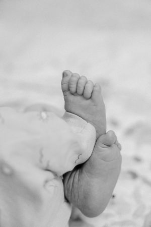 Black and white close-up image of tiny newborn baby feet against a soft white background.