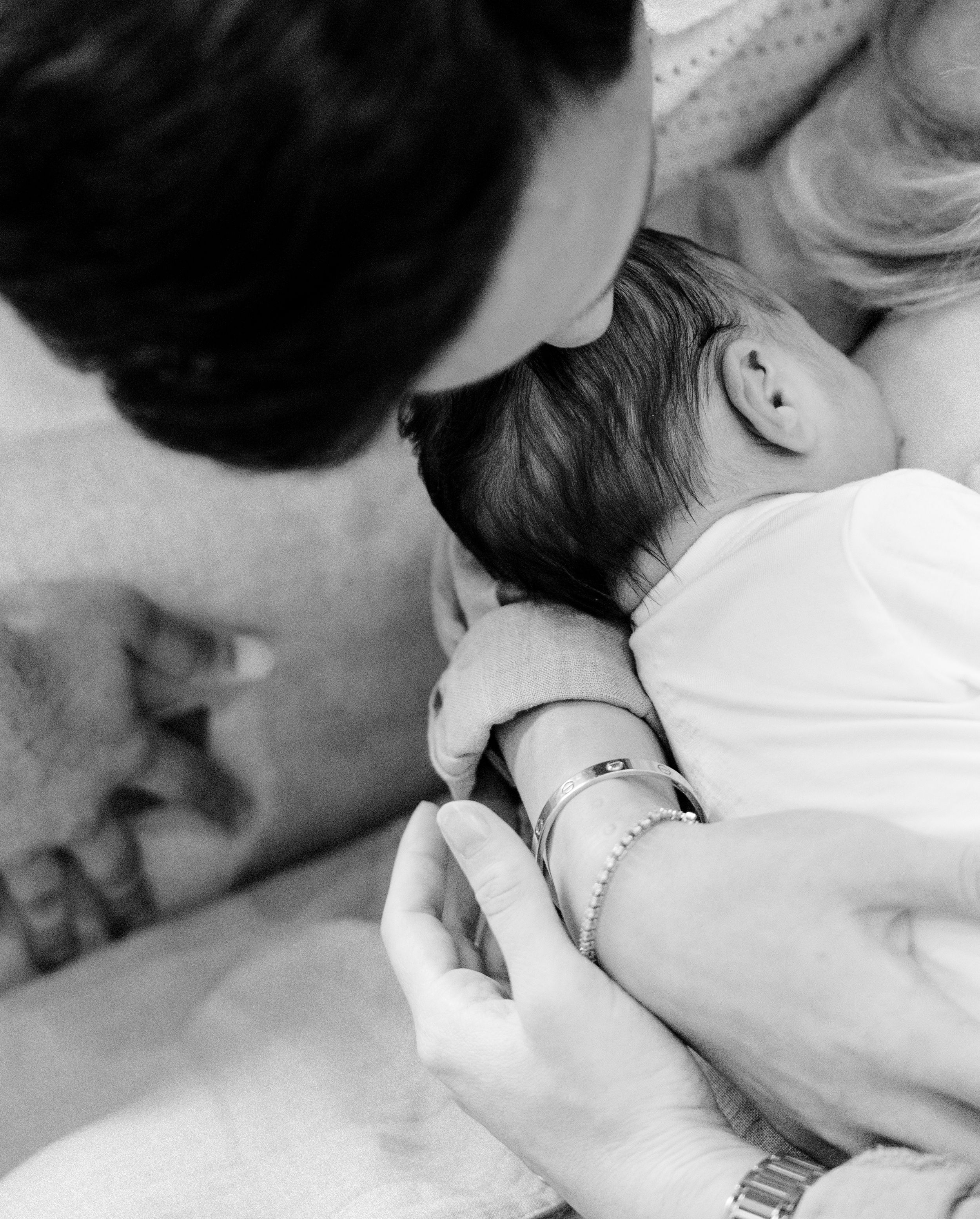 A tender black and white photograph showing a gentle kiss on a baby's forehead.