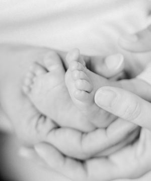 A serene black and white close-up photograph of a sleeping newborn baby's face and tiny hand.