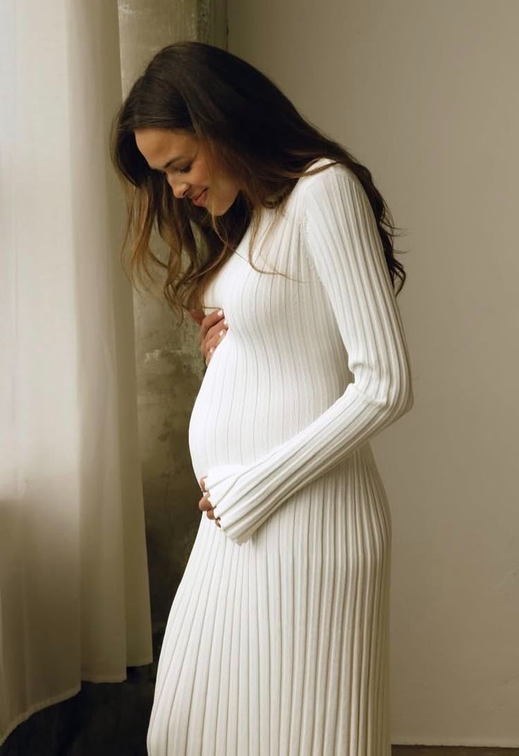 Series of photos showing a pregnant figure in a cozy white ribbed sweater dress against a neutral wall.