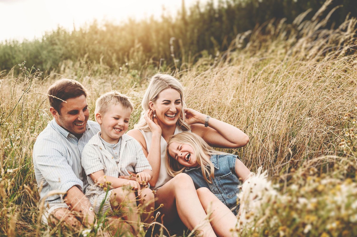 Family sharing joyful moments together in tall wheat field during sunset.