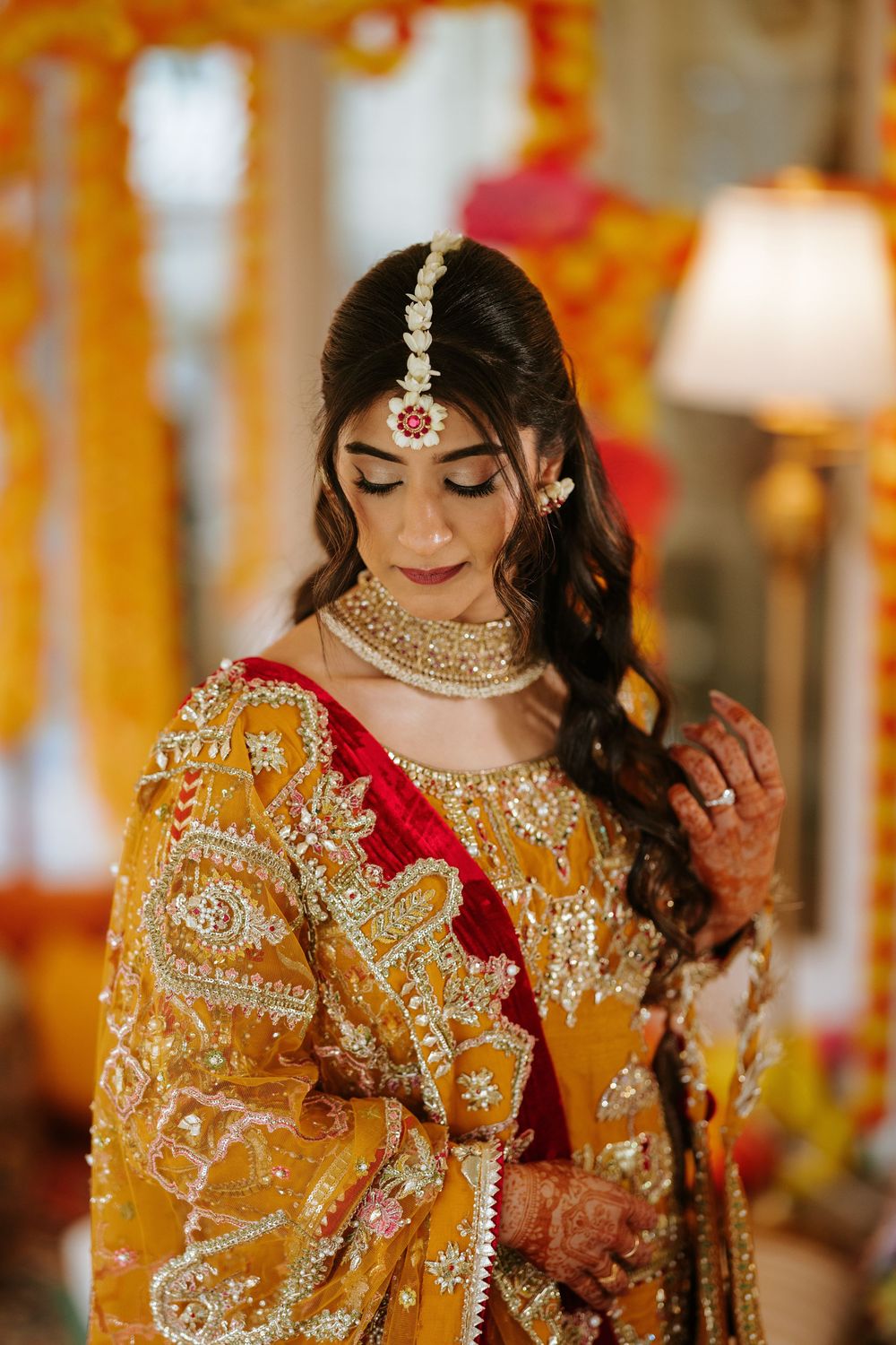 Close-up details of ornate gold embroidery and jewels on traditional South Asian bridal attire glowing in warm lighting.