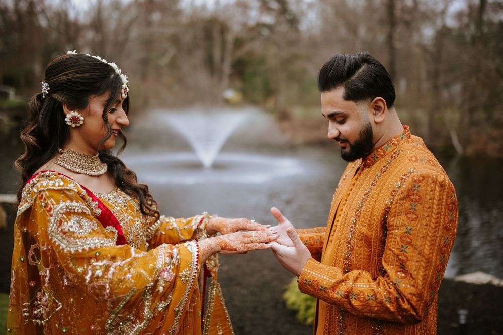 A couple in traditional Indian attire poses together by a lake during an autumn engagement photoshoot.