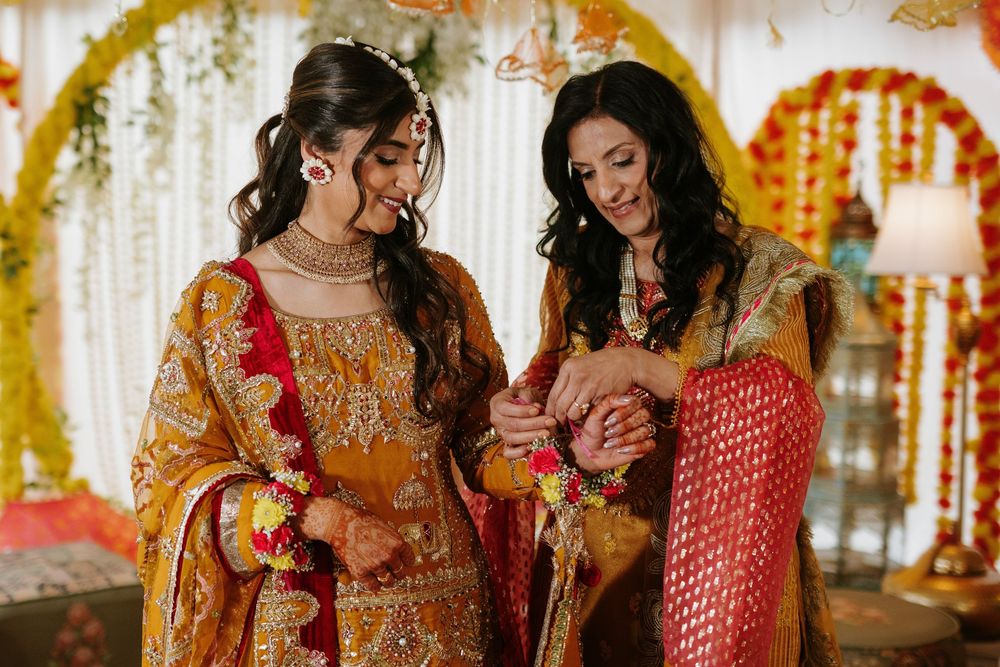 Two women in traditional South Asian wedding attire share a joyful moment during celebrations.