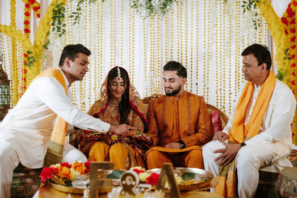Traditional Indian wedding ceremony with guests seated on floor during puja ritual with floral backdrop and decorations.