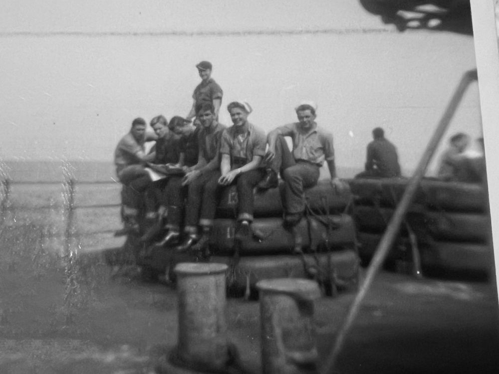 Vintage military photograph showing soldiers seated on equipment in the field.