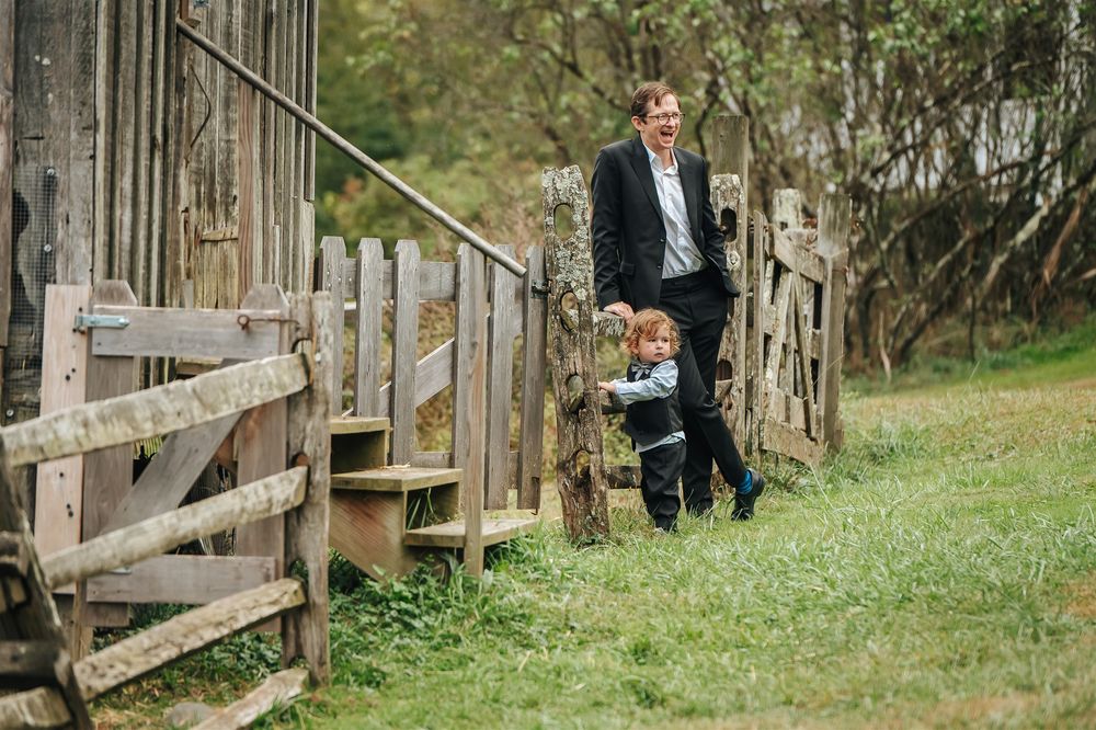 Wooden fence pathway leads through green grass in rustic outdoor setting.