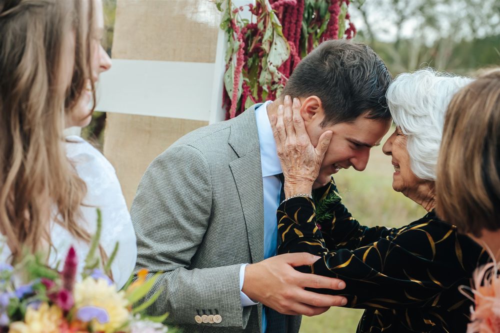 Couple in wedding attire share an intimate moment in an outdoor garden setting with colorful floral decor.