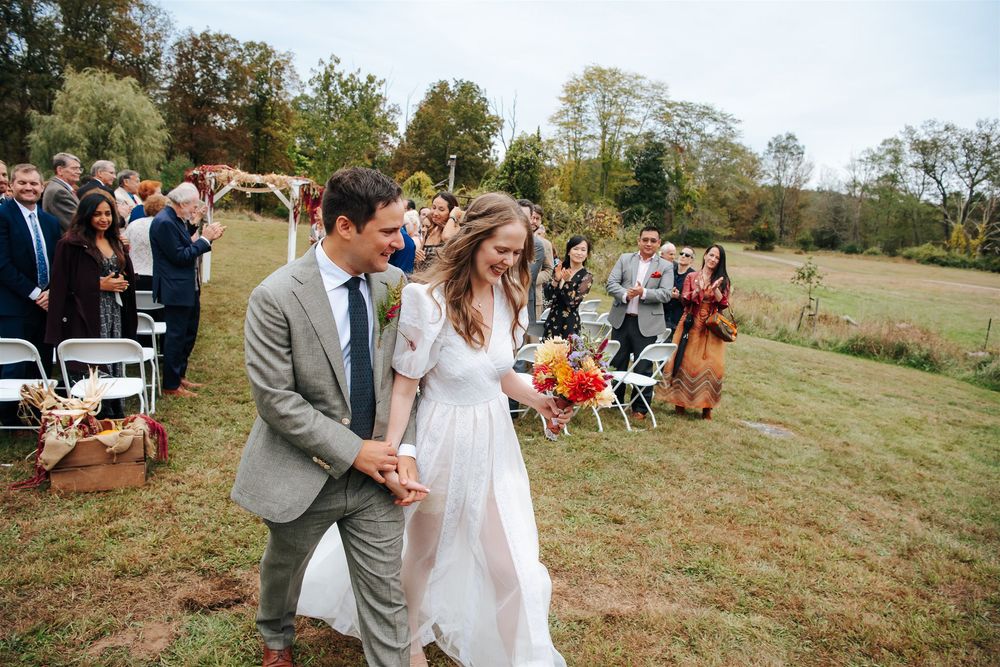 Outdoor autumn wedding ceremony set against a backdrop of trees and natural landscape.