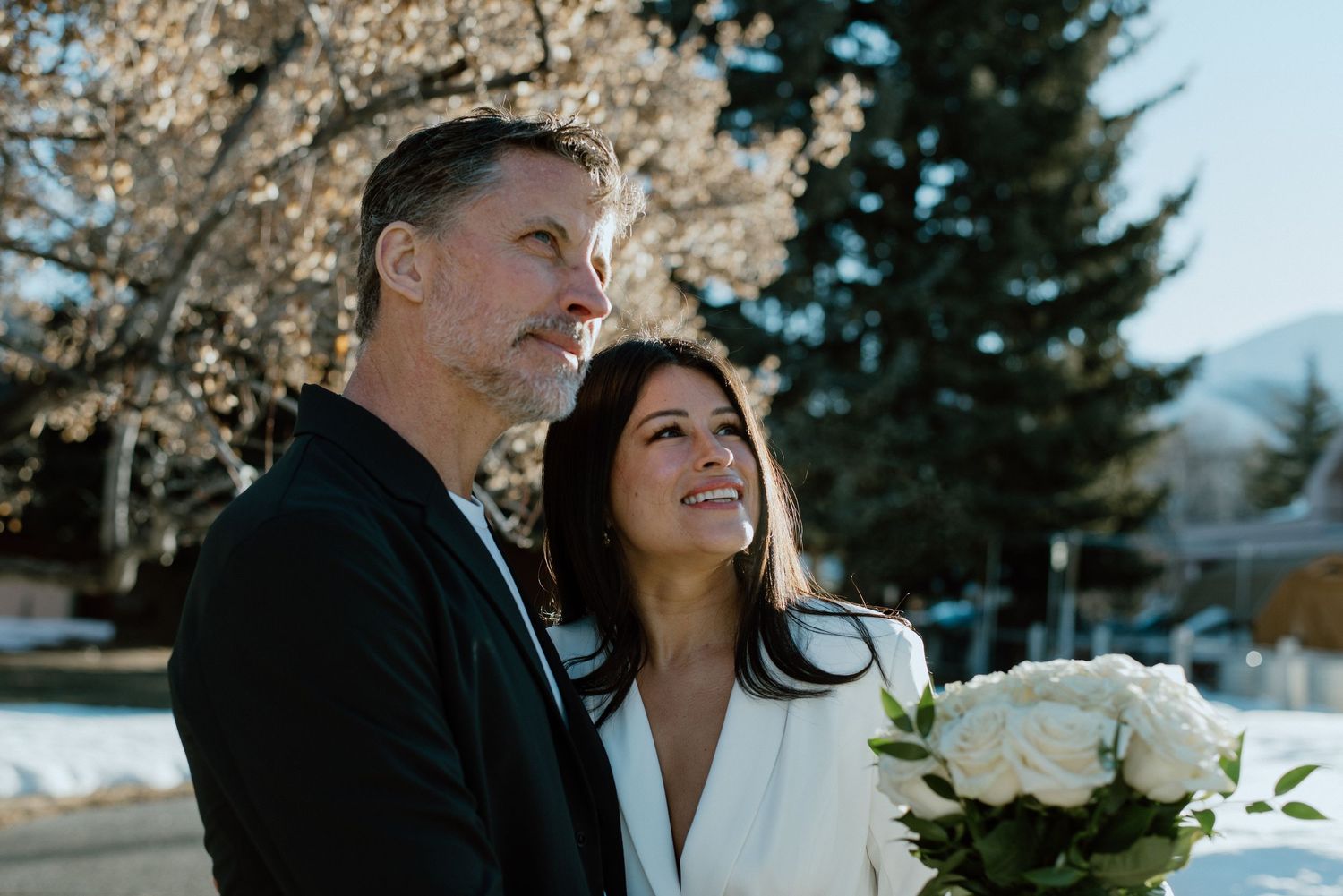 A couple in a suit and modern wedding dress have candid smiles during their elopement at the Blaine County Courthouse in Hailey, Idaho.