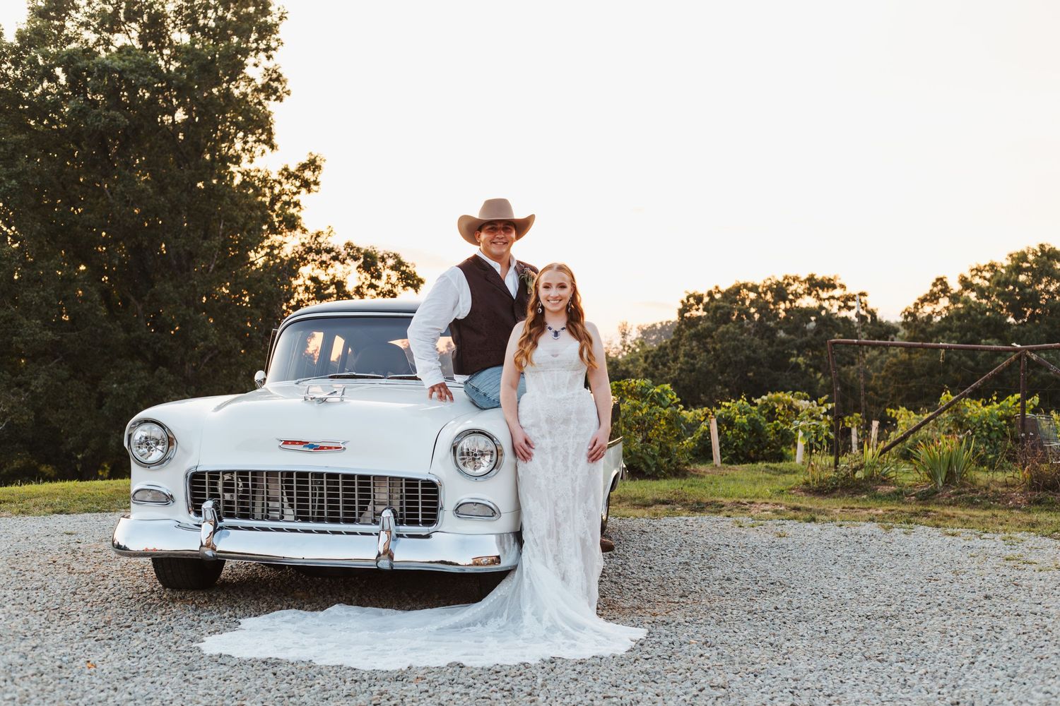 Classic white Chevrolet car parked on gravel during sunset.