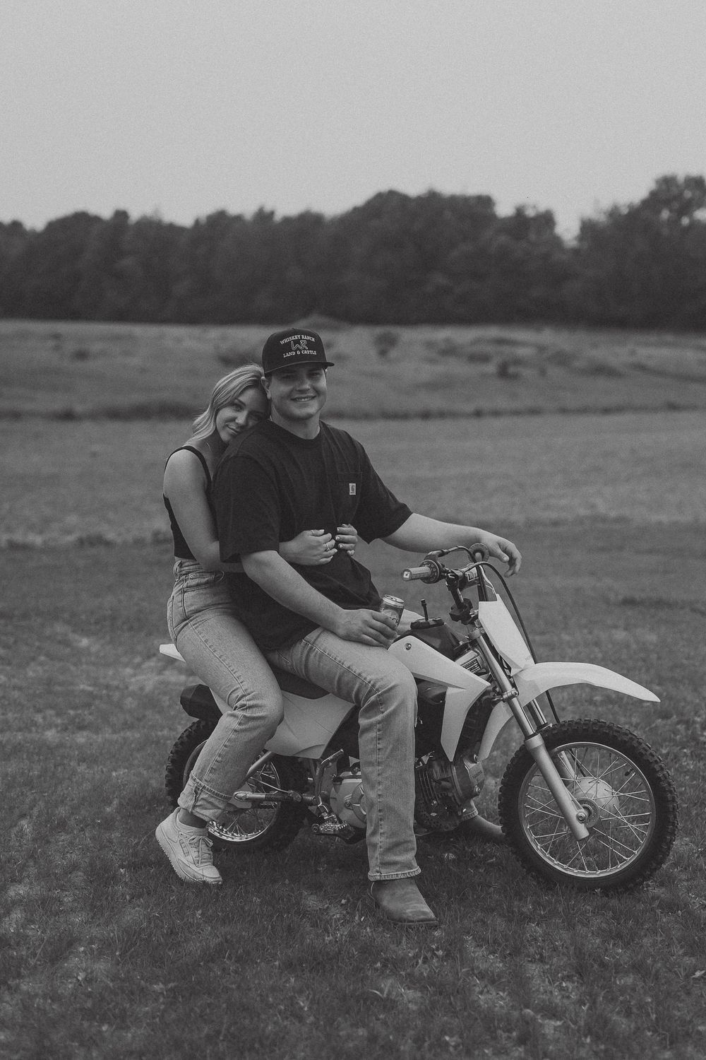 Black and white photos show someone reclining next to a classic off-road dirt bike in a grassy field.