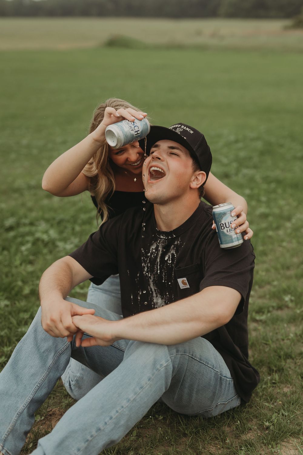 Person sitting on grass enjoying a cold beverage outdoors.