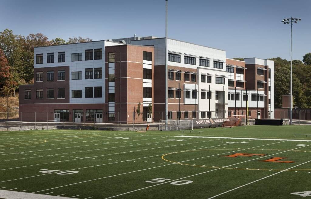 A sequence of five exterior views showcasing an athletic field and modern school buildings with brick architecture.