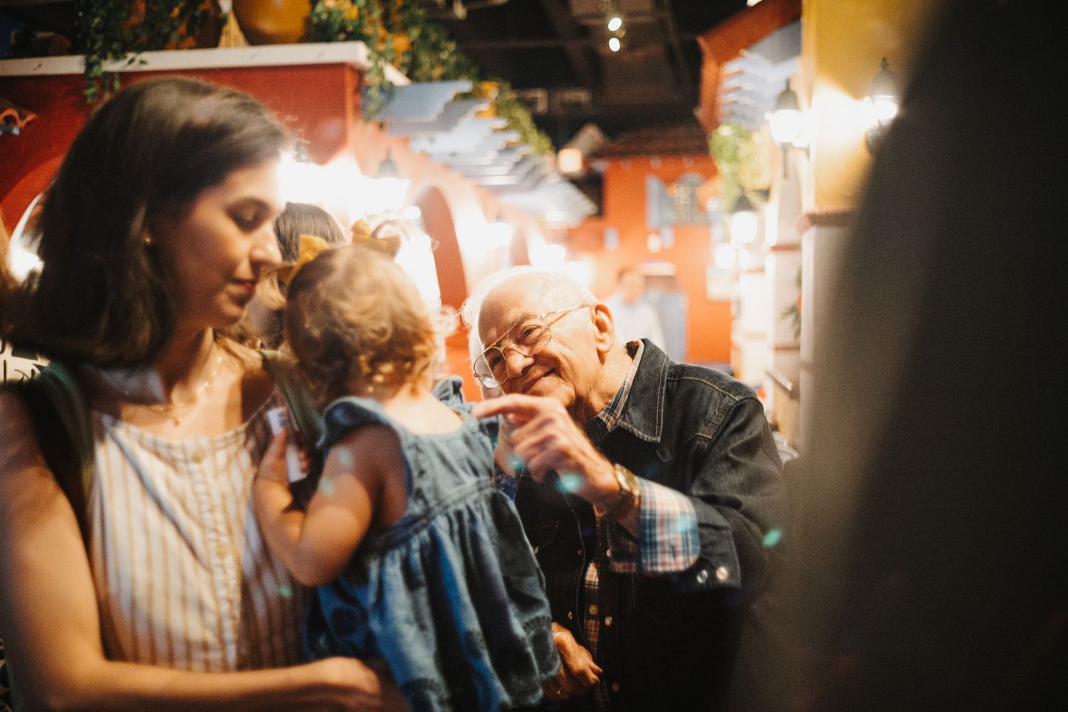 People sharing a joyful moment together with laughter and sparklers in a dimly lit setting.