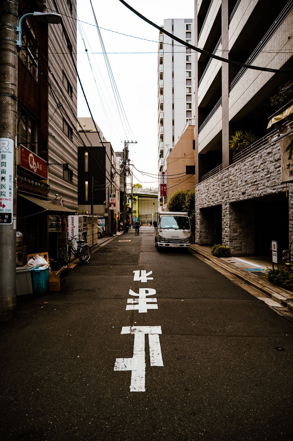 White directional arrows painted on a steep urban street between tall buildings in Japan.