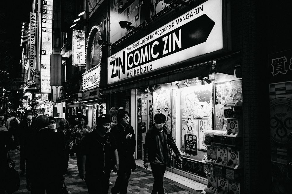 Neon signs illuminate a dark urban alleyway at night in Japan, creating a moody cyberpunk atmosphere.