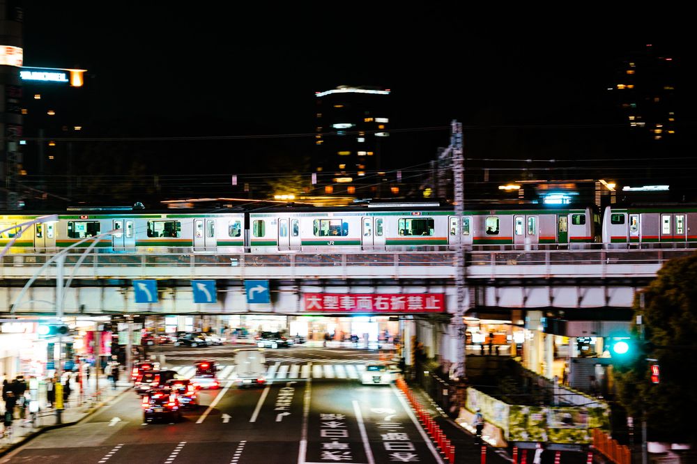Bustling Japanese street market at night with bright neon signs and vendor stalls stretching into the distance.