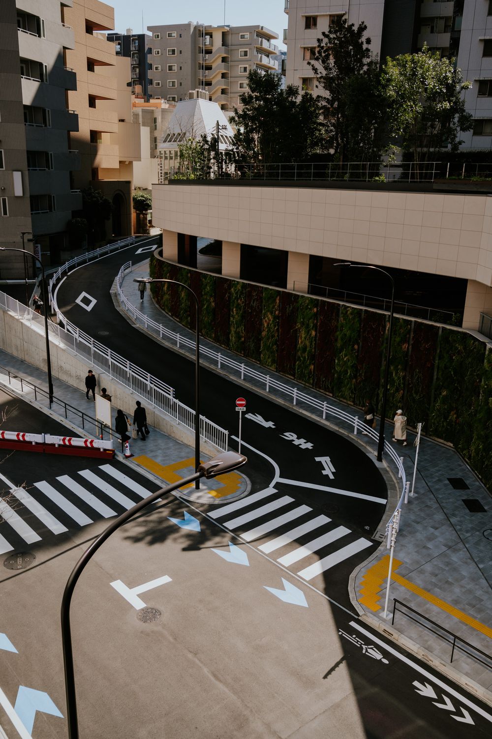 Modern curved walkway with directional arrows painted on concrete between urban apartment buildings.