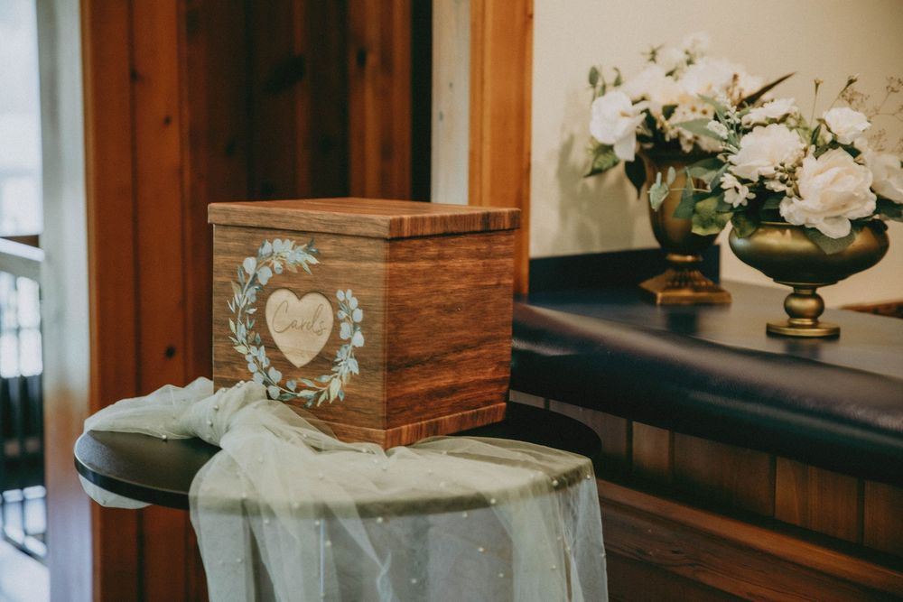 White orchid floral arrangements in brown wooden boxes create an elegant rustic display on a dark surface.