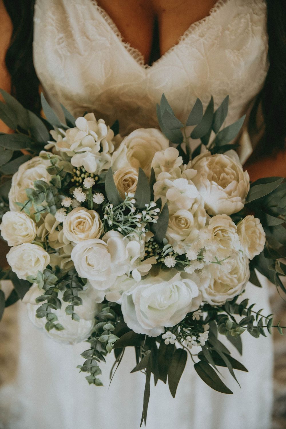 Five coordinating wedding bouquets featuring white roses and eucalyptus greenery arranged in a minimalist style.