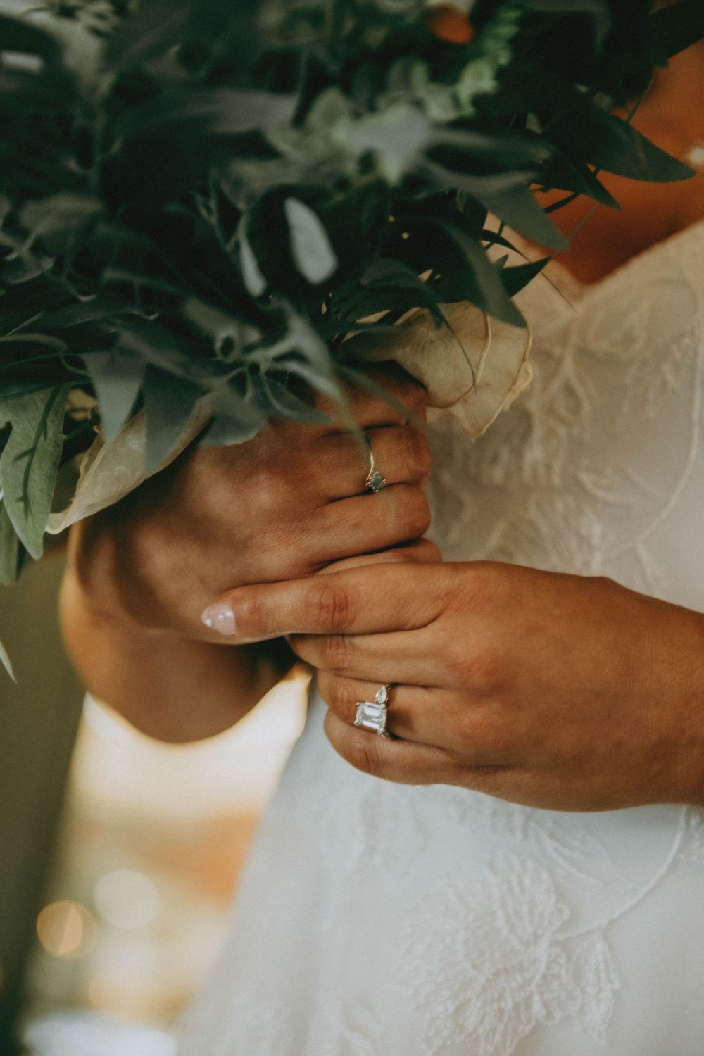 Close-up series of hands holding elegant floral bouquet against white wedding dress details.