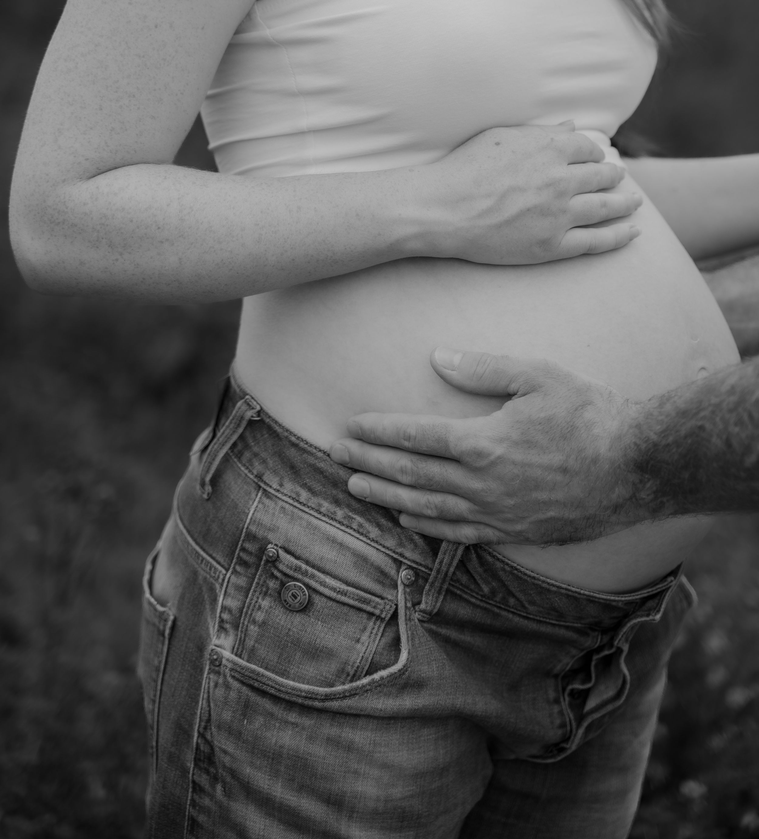Close-up black and white image of someone's midsection wearing jeans, showing bare skin above the waistband.