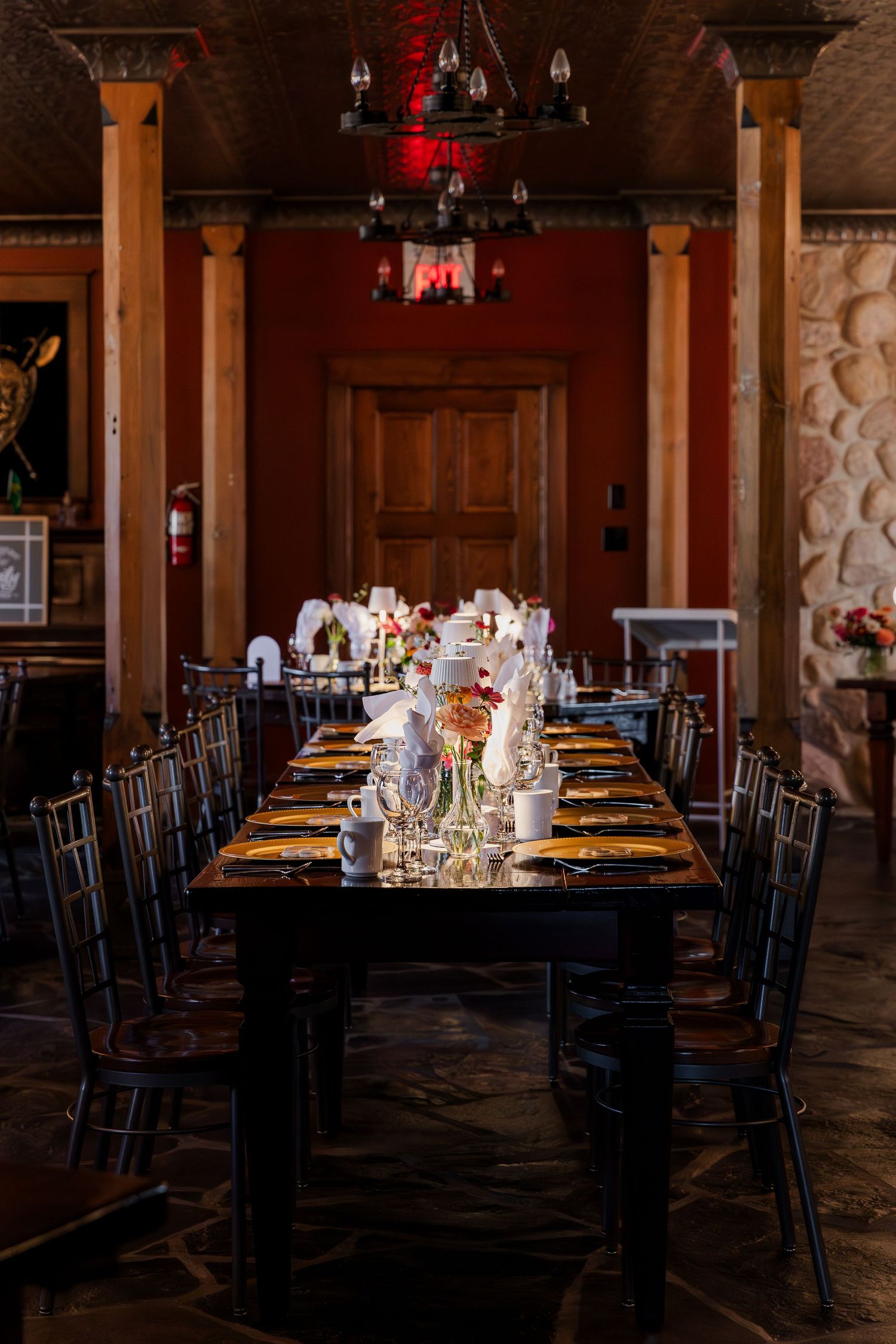 Elegant wedding setup with dark wooden tables, stone walls, and warm lighting, an intimate atmosphere at Hauser Hall in Kitchener, Ontario.