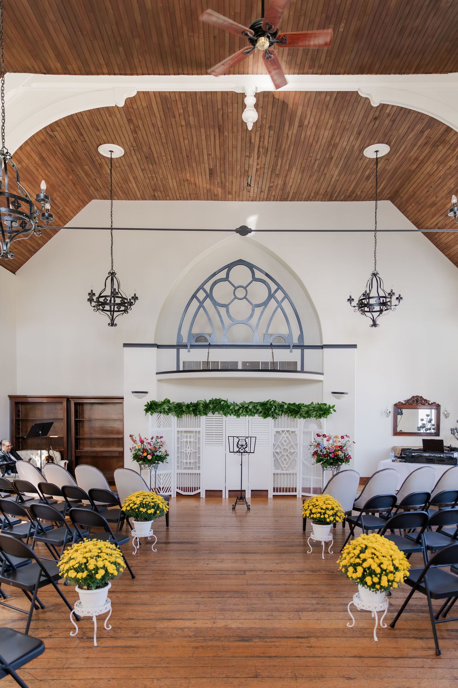 Wedding chapel interior with vaulted wooden ceiling, white walls, and elegant chandeliers at Hauser Hall in Kitchener, Ontario.