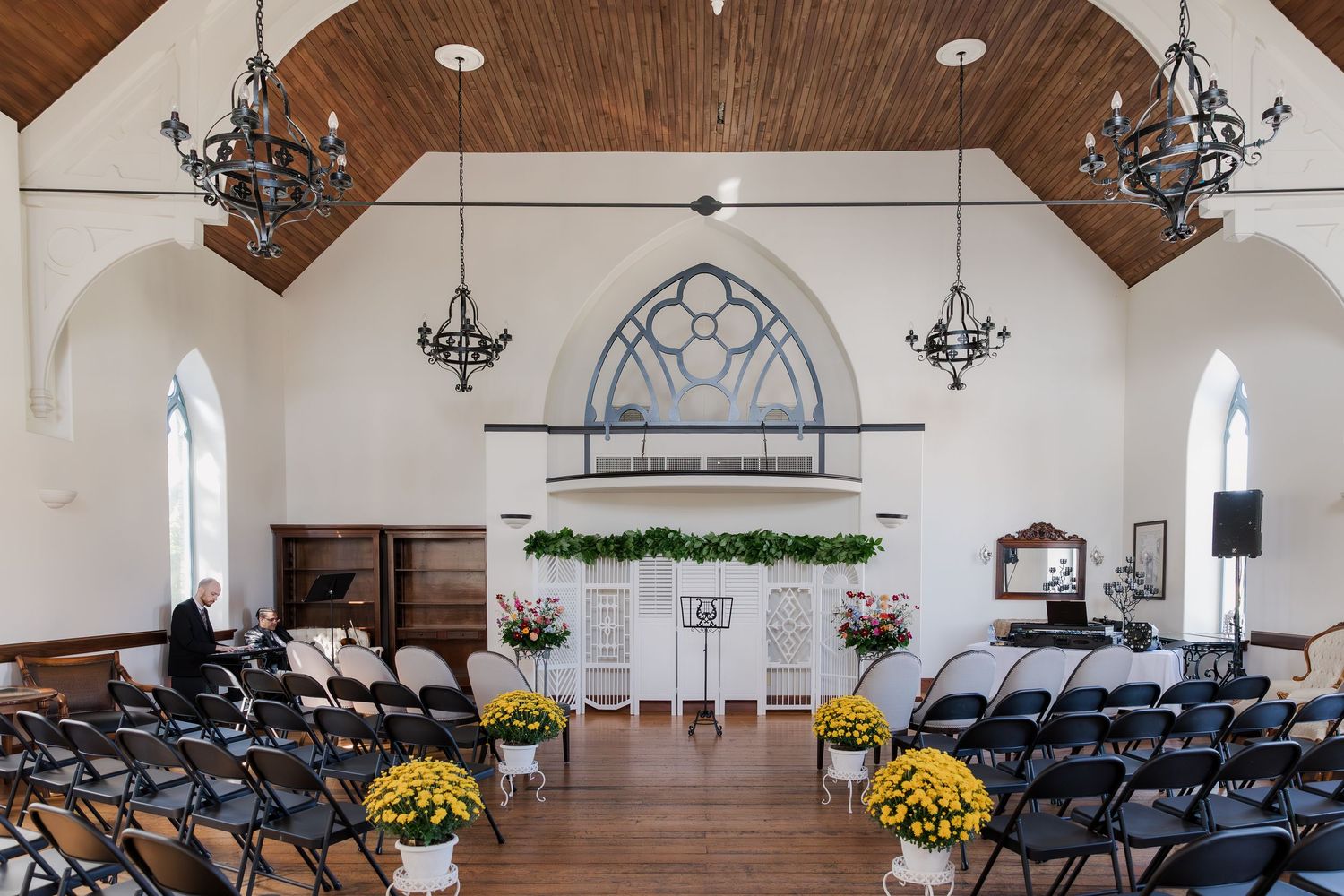 Chapel-style space with wooden beam ceiling, chandeliers, and rows of chairs for ceremony seating at Hauser Hall in Kitchener, Ontario.
