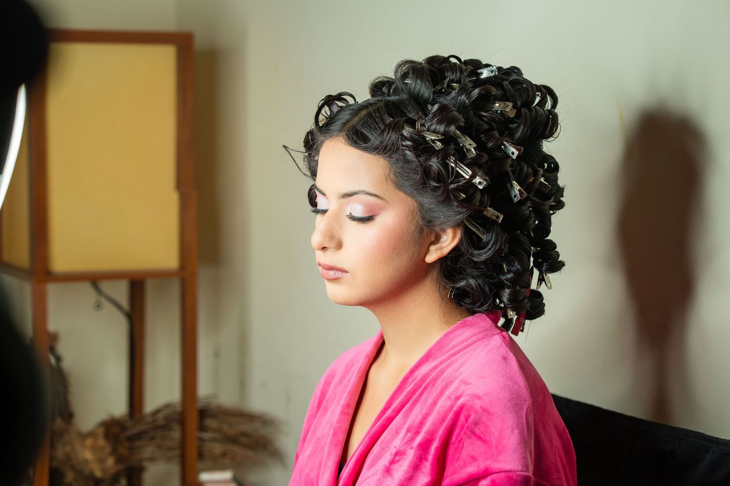 Person with curly dark hair wearing a bright pink top poses in a series of artistic portraits.