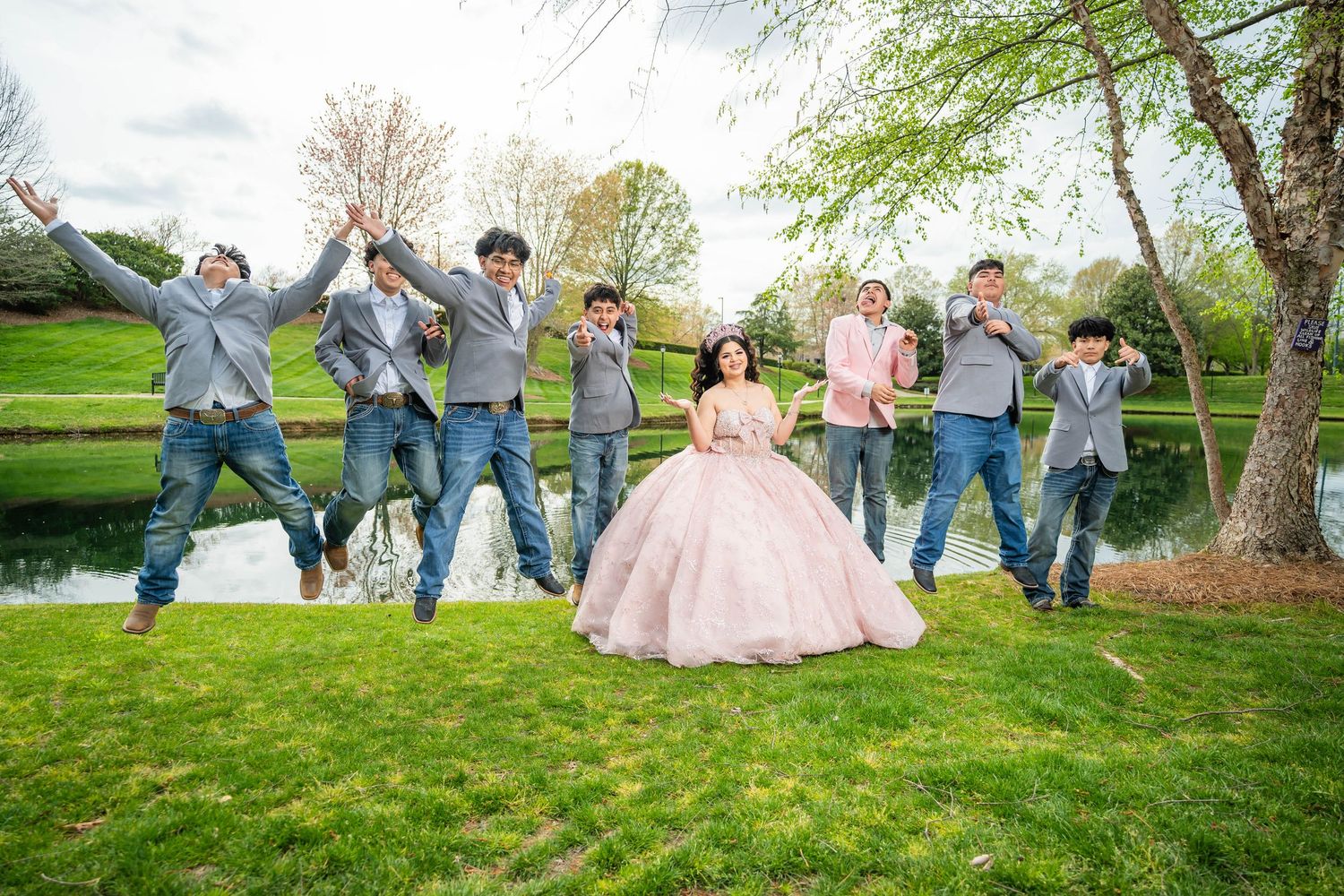 A group of people sit casually on a grassy hillside during a sunny outdoor photo session.