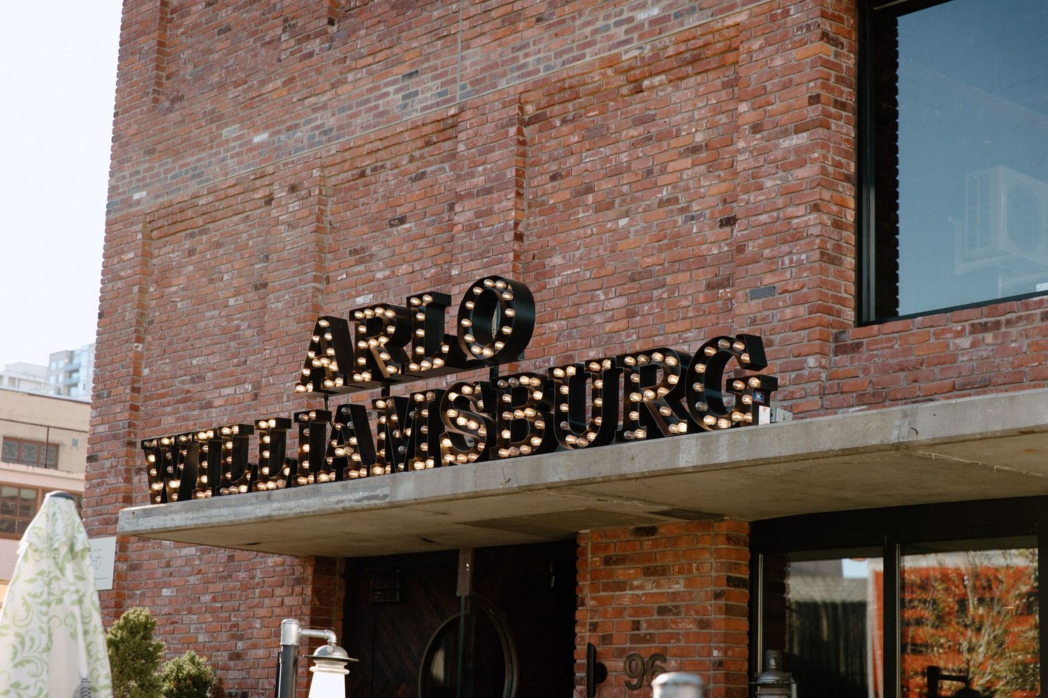 Exterior view of a brick building with string lights and signage.