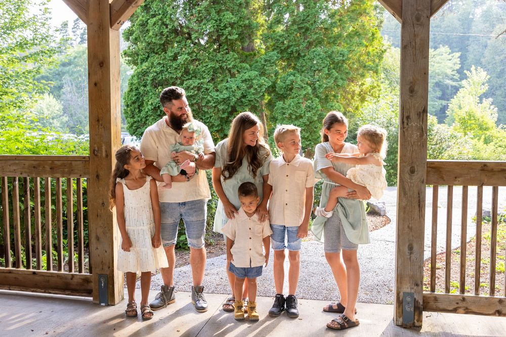 Family of 8 at Orono park under a gazebo looking at one another