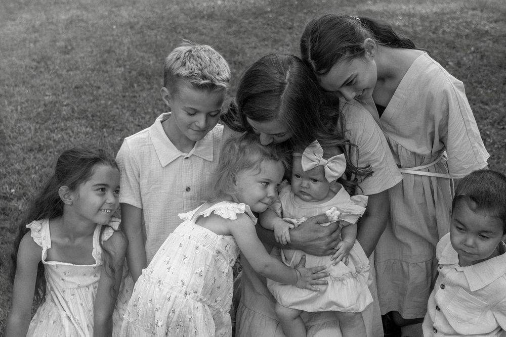 A black and white photo of a mom and her 6 kids all cuddled in closely