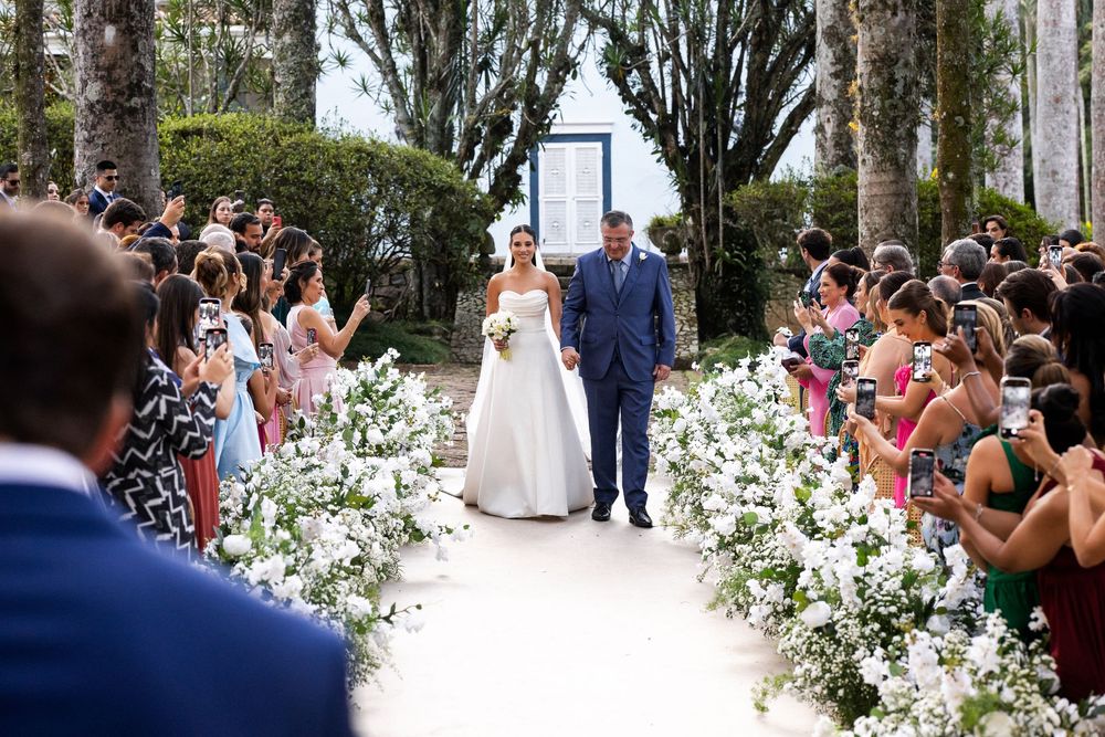 Wedding ceremony setup outdoors with white floral decorations and guests seated on either side of the aisle.
