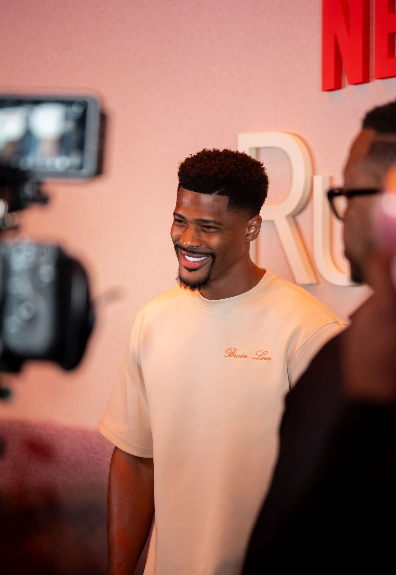 Netflix event attendee in cream colored shirt being interviewed by media.