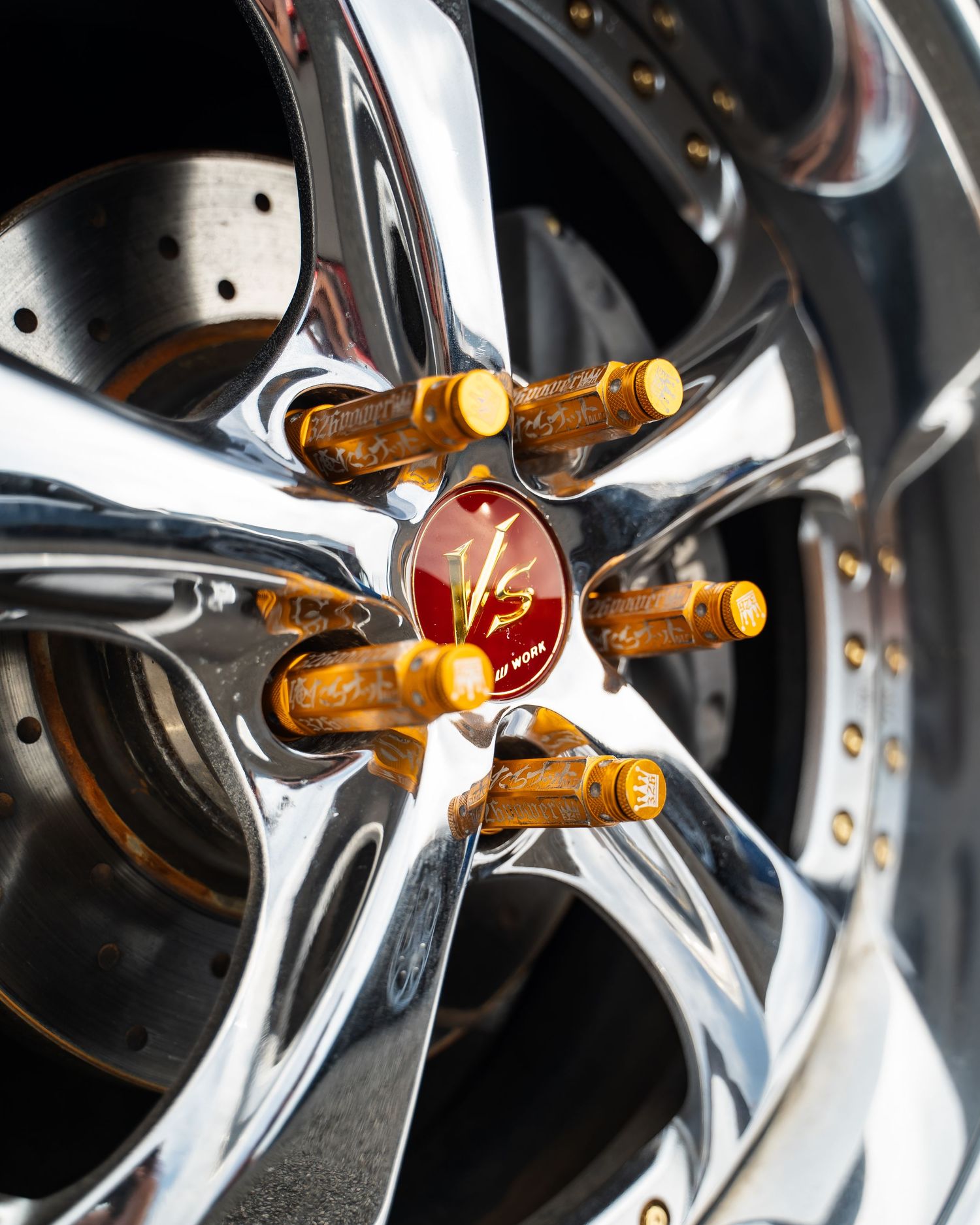 Close-up of polished chrome wheel spokes with gold-colored lug nuts.