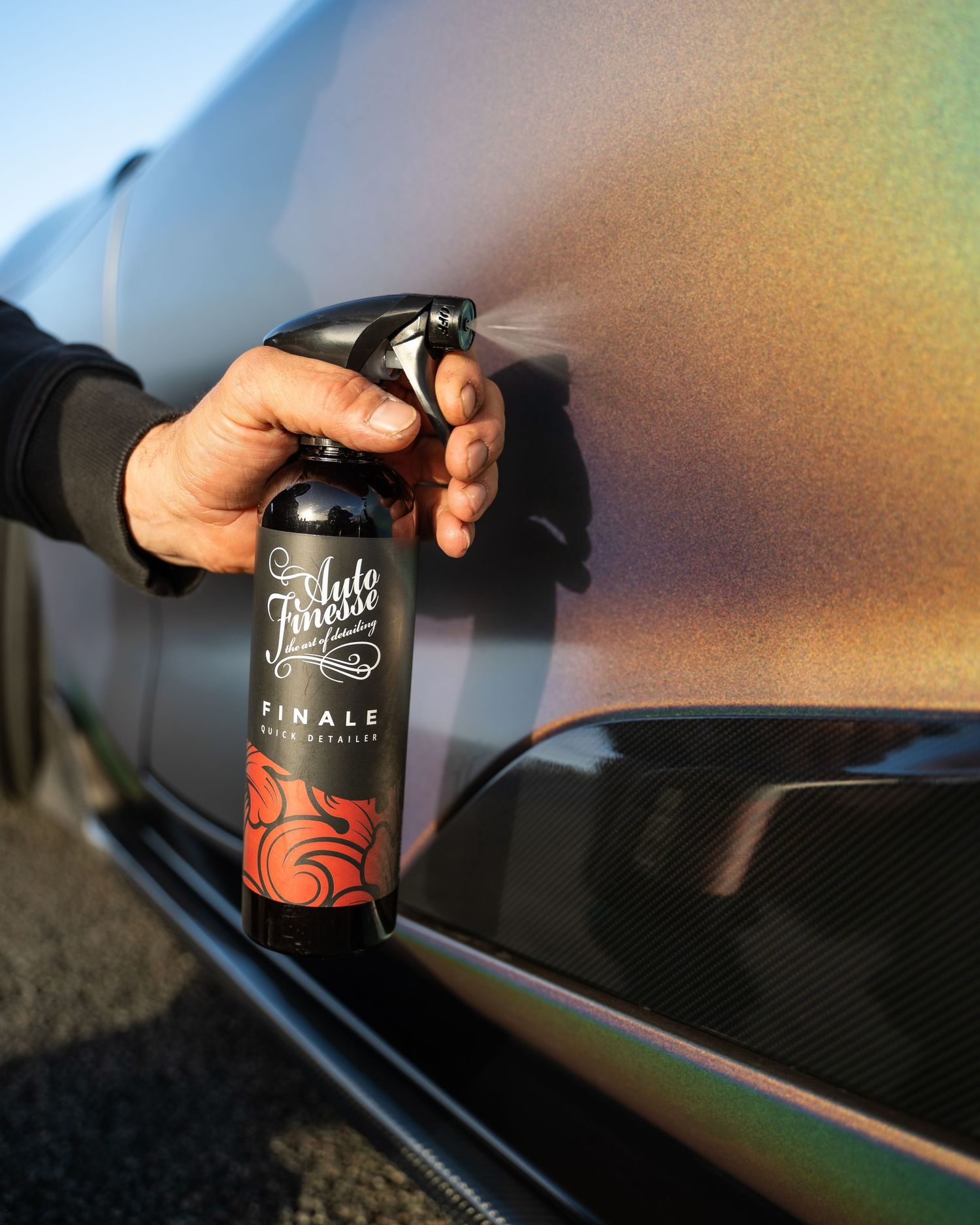 Car detailing product being applied to a carbon fiber automotive surface.