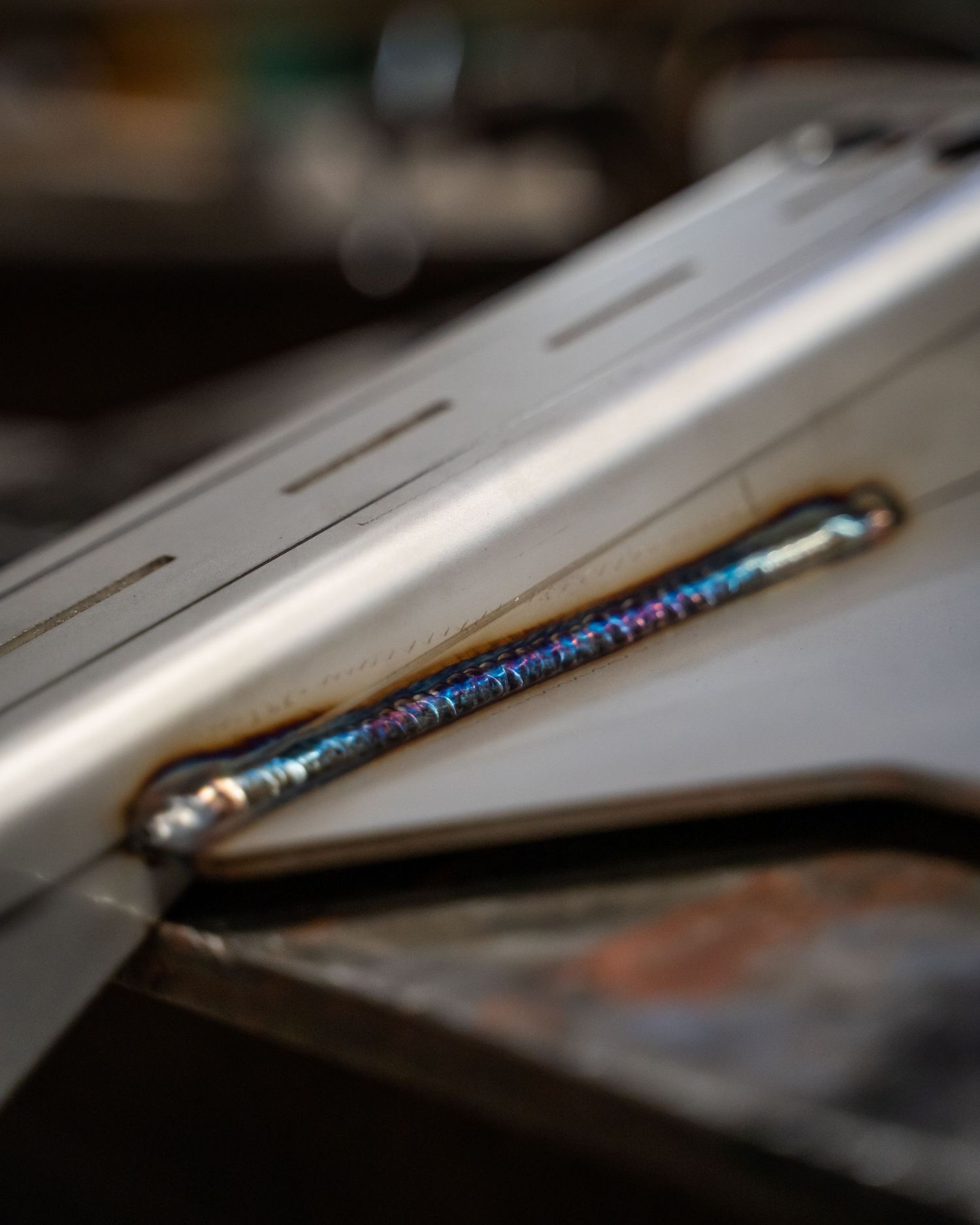 Macro shot of a metallic surface with iridescent blue welding marks.