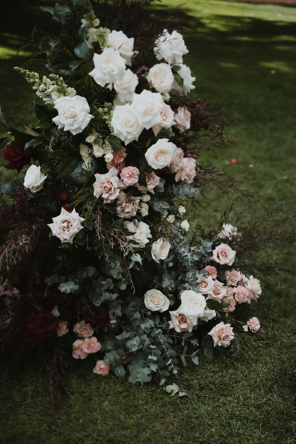 Elegant floral arrangement with white and pink roses on green grass.