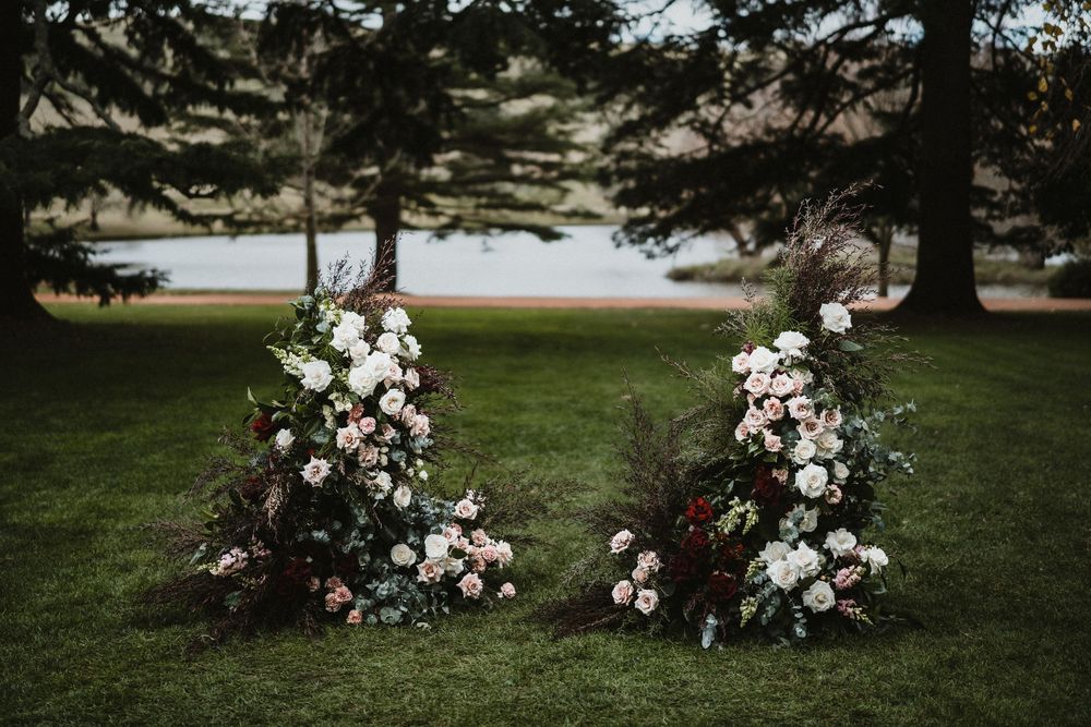 Outdoor wedding ceremony setup with floral arrangements lining a grassy path.