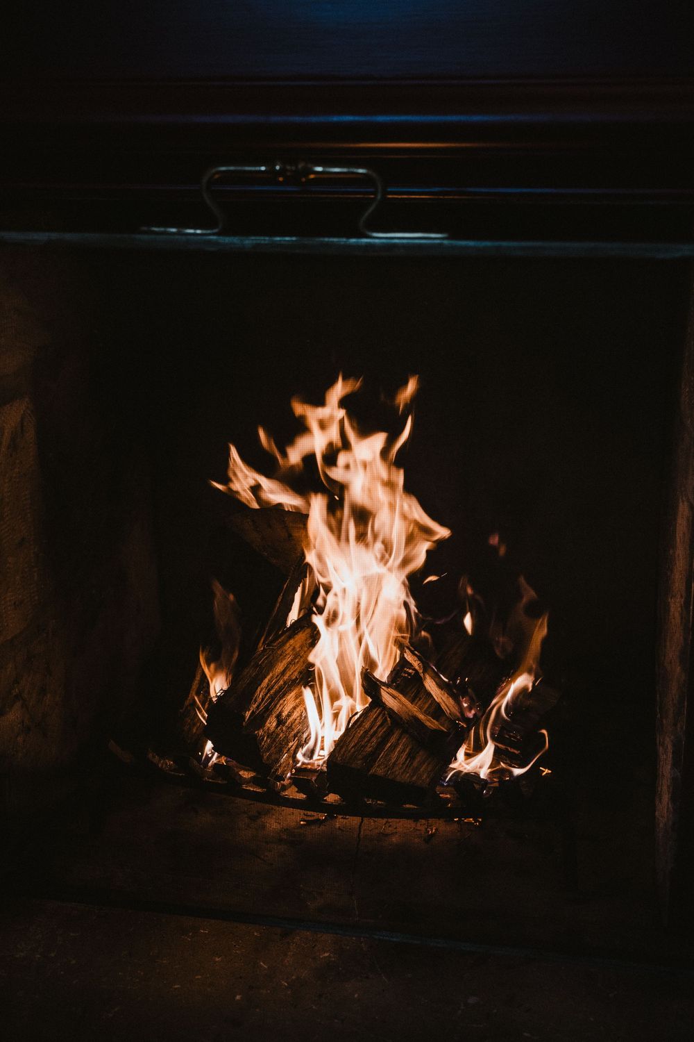 Roaring fireplace with bright orange flames against a dark background.