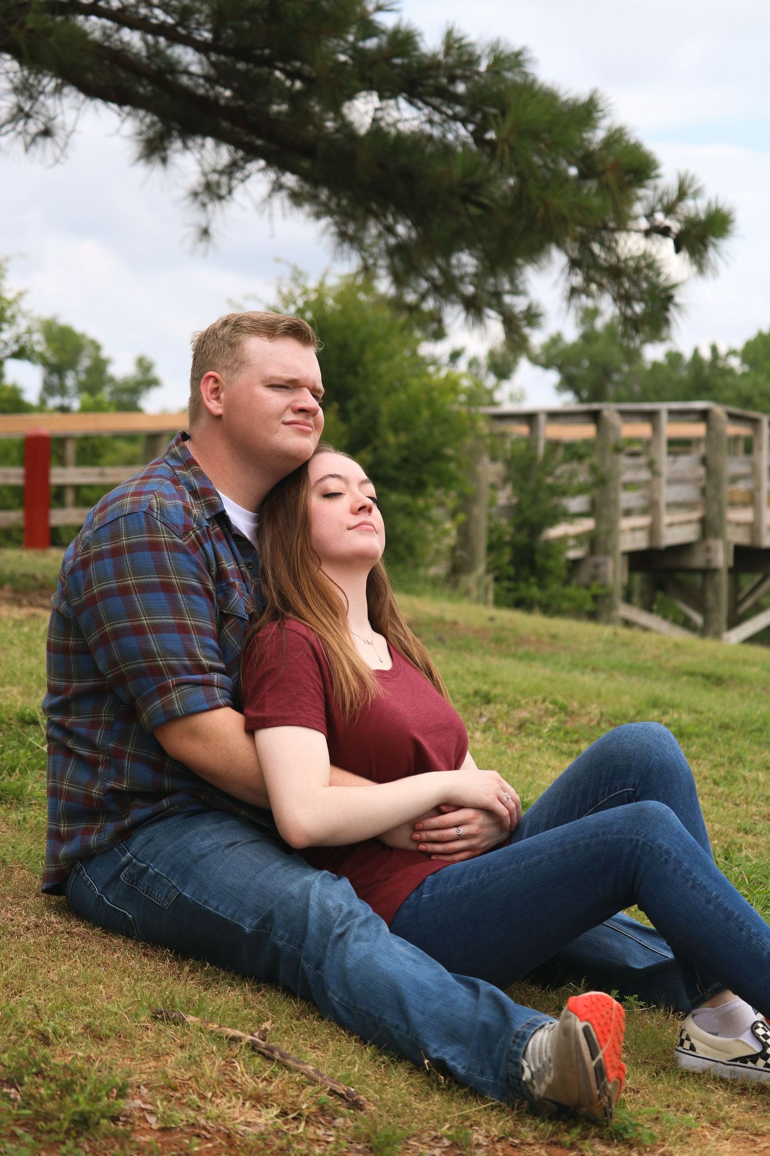 A couple relaxes together on a grassy hillside on a sunny afternoon.